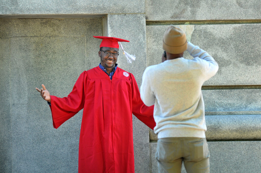 A graduating senior poses for photos at the base of the Belltower.