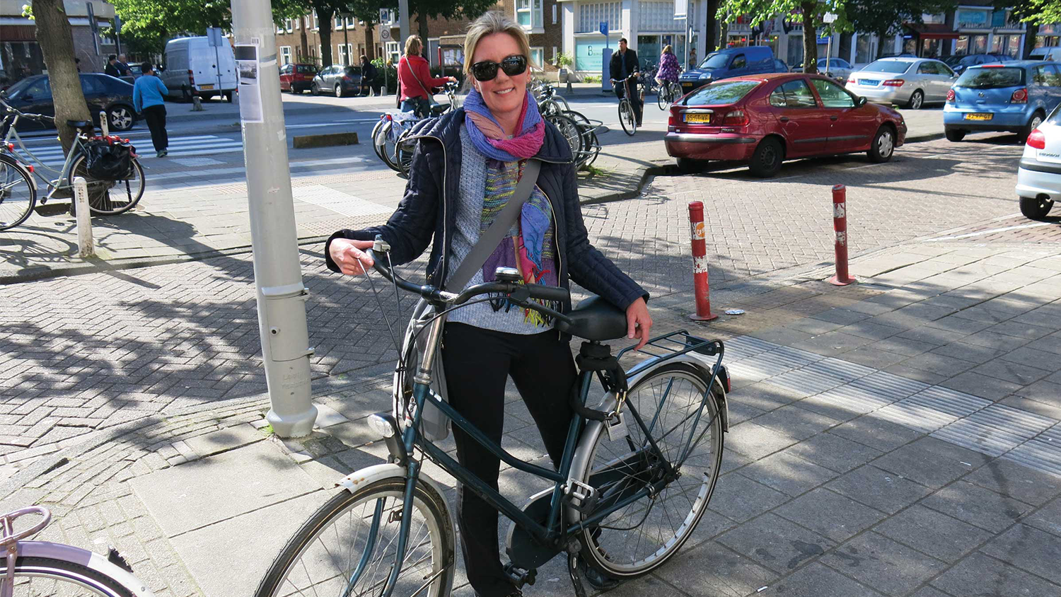 Jennifer Tooles poses with a bike on a busy street in Amsterdam.