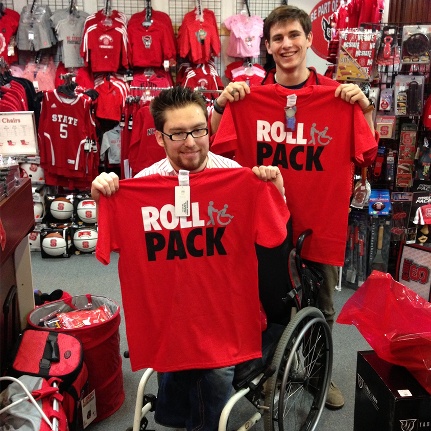 Will Privette and Andy Walsh inside Wolfpack Outfitters holding RollPack t-shirts.