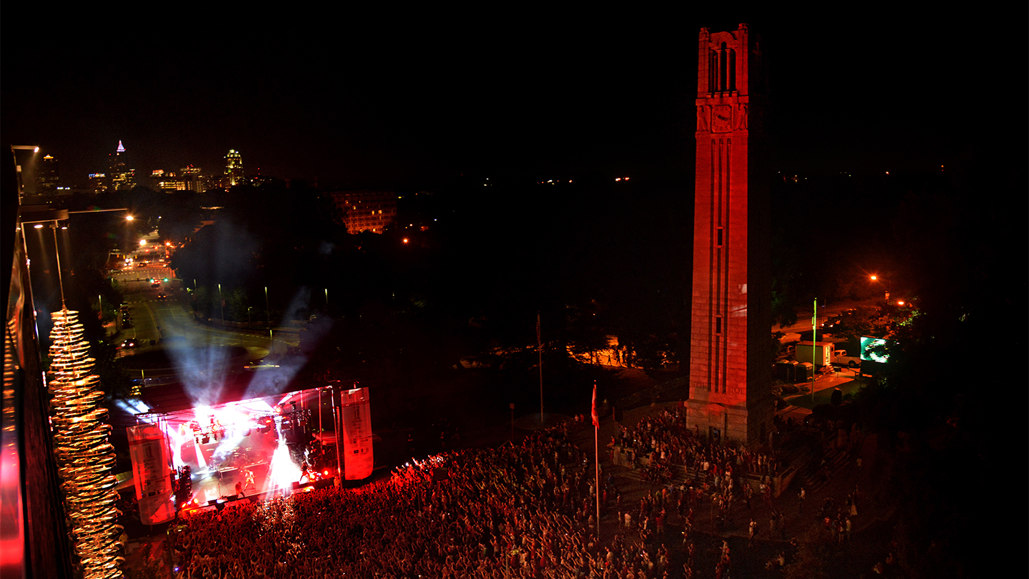 Looking down at the Belltower, which is illuminated red with a concert taking place on Hillsborough Street at night
