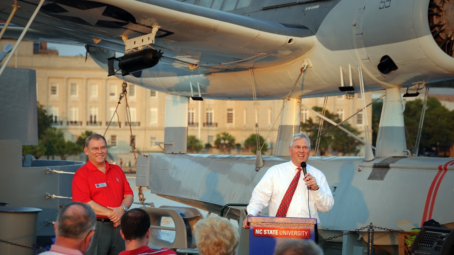 Benny Suggs, left, listens as Chancellor Randy Woodson addresses alumni at a reception on board the USS North Carolina in 2010.