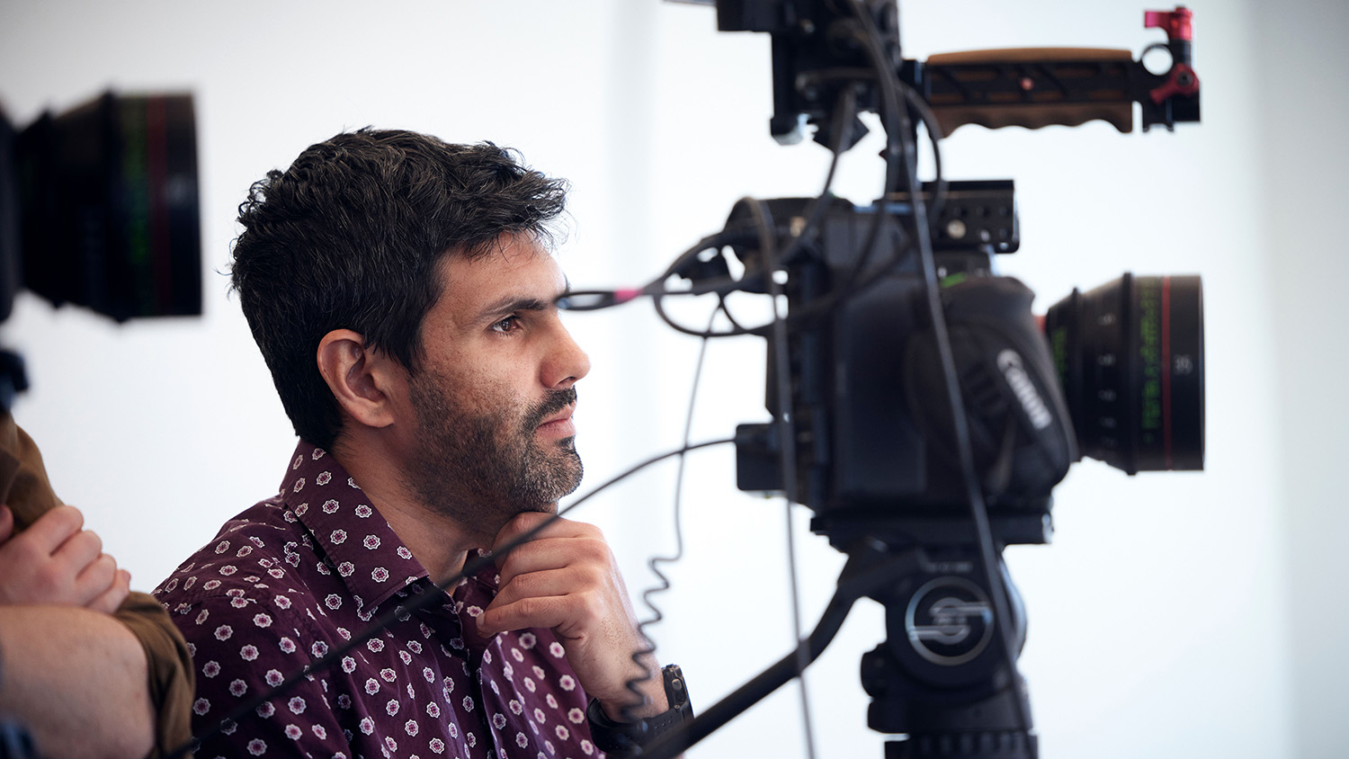 A man sits behind a camera.