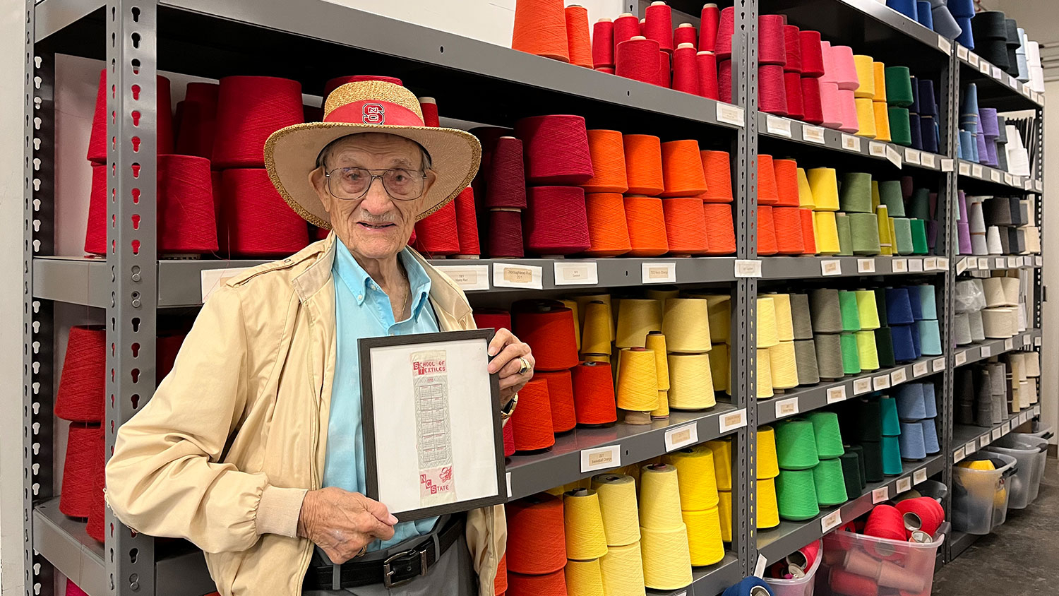 Willie Bowen stands with a bookmark in front of a colorful background at the Wilson College of Textiles