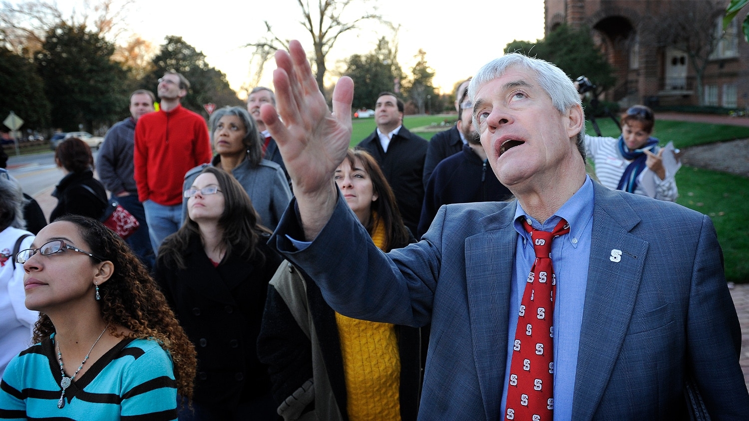 Tom Stafford directs a crowd's attention to the Belltower from the lawn of Holladay Hall