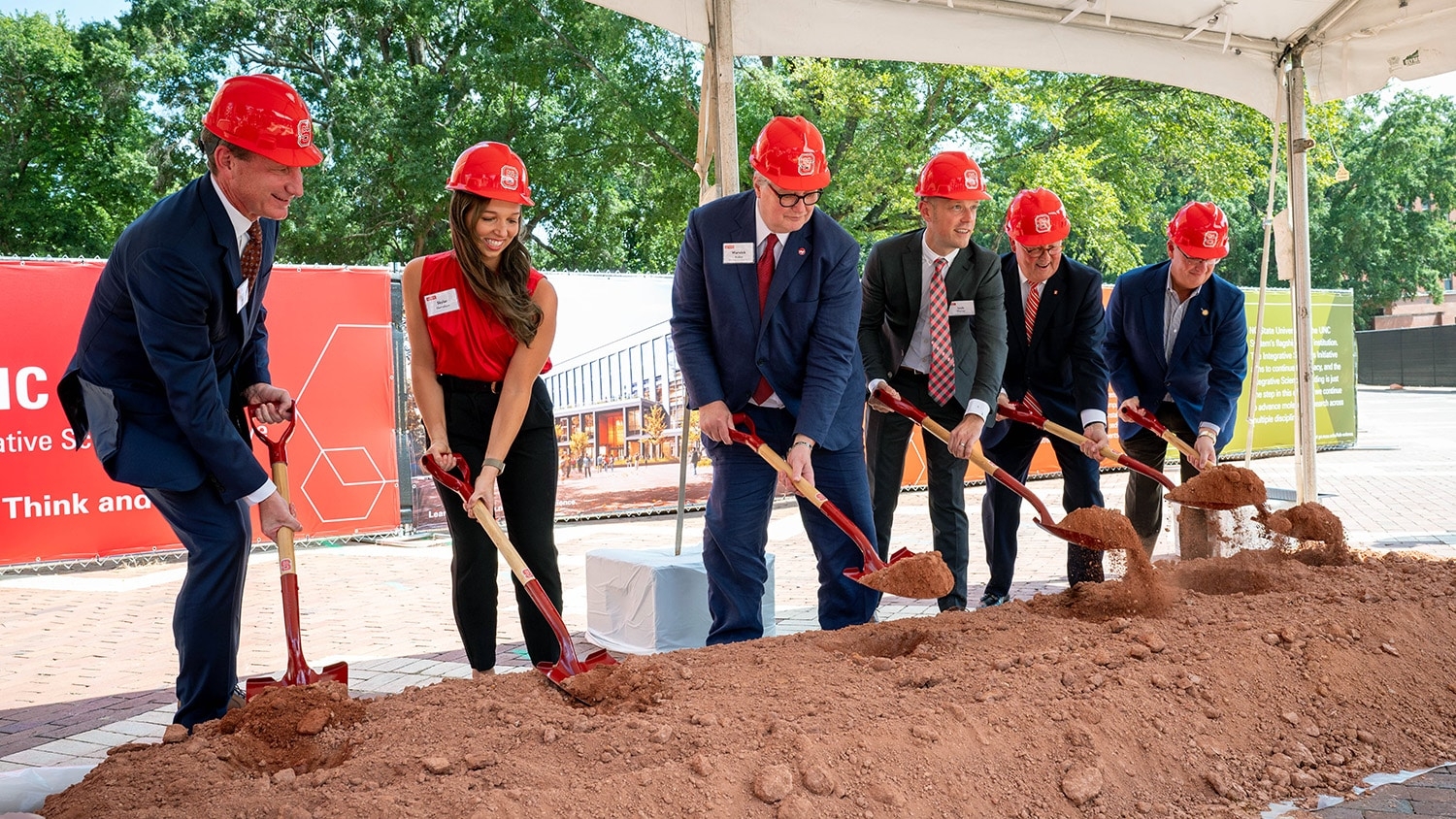 A group of NC State leaders in hard hats "break ground" on the new Integrative Sciences Building.