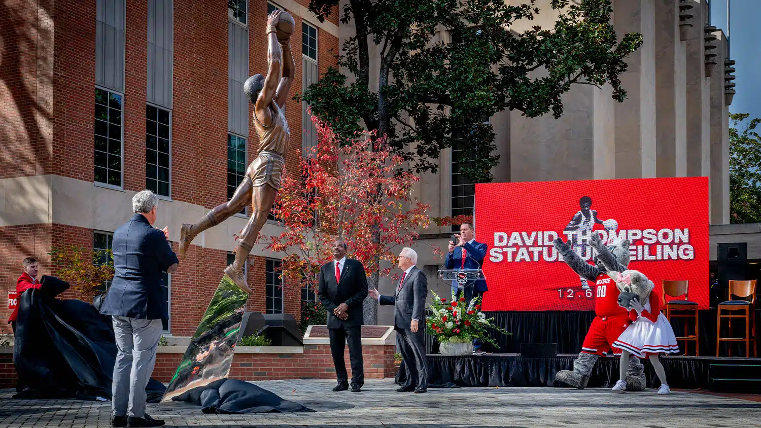 David Thompson and other attendees watch as a new statue in his likeness is unveiled next to Reynolds Coliseum.