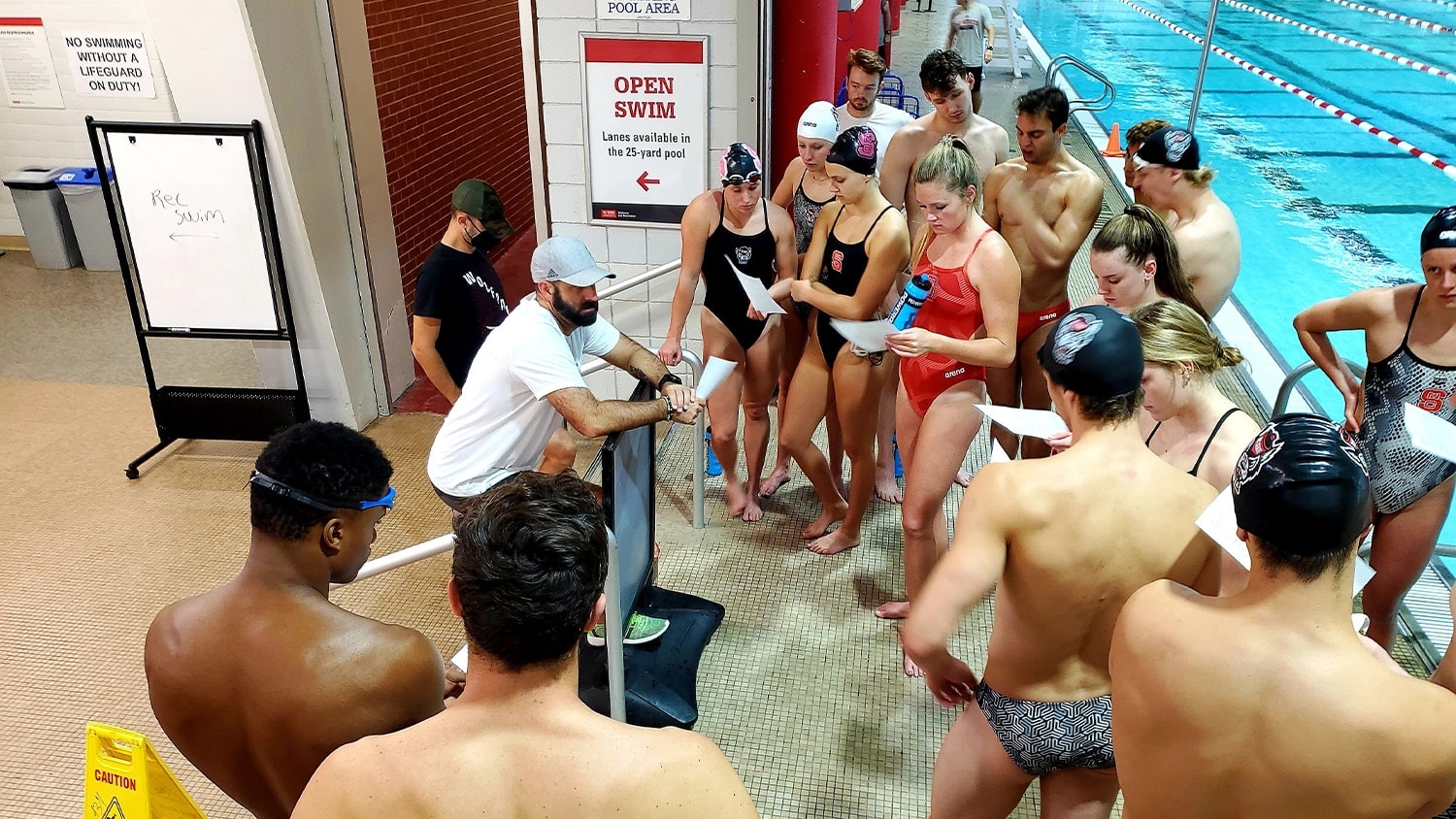 Men's Swimming Coach Braden Holloway addresses swimmers training for the 2024 Olympics by the pool in Carmichael Gymnasium