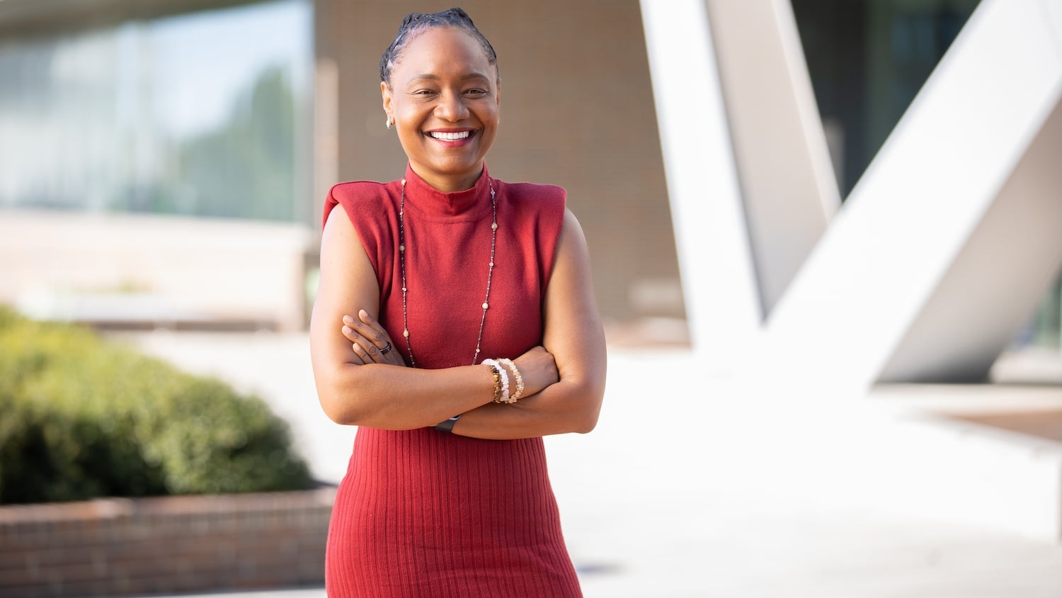 Two-time NC State alumna Rashida A. Hodge stands smiling wearing a red dress.