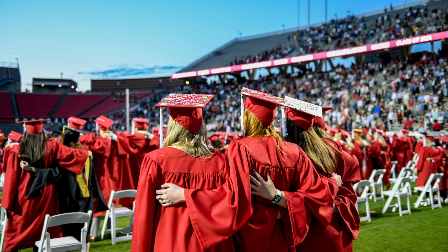 Three NC State graduates stand side by side during the ceremony in Carter-Finley Stadium.
