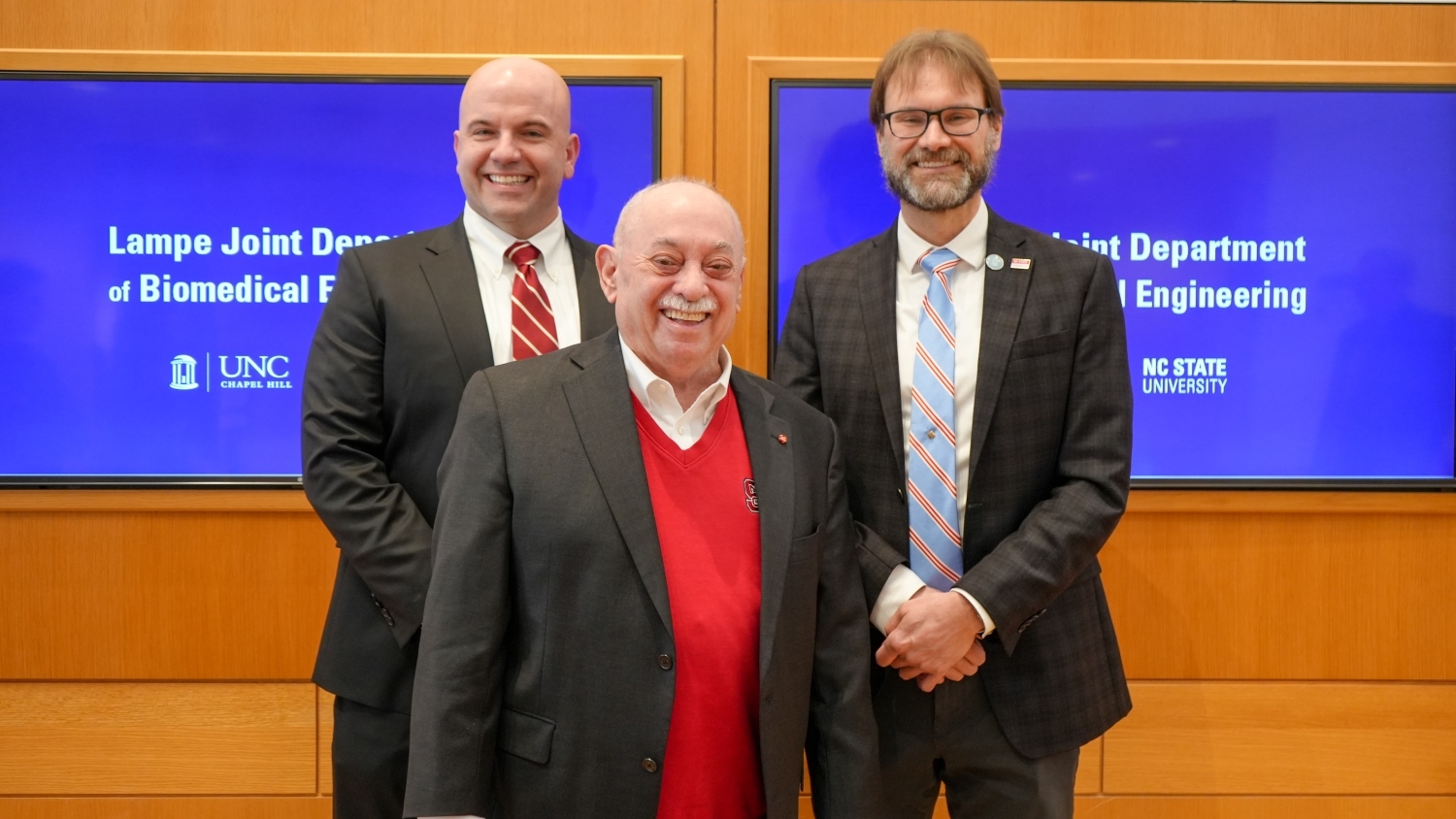 Dean Jim Pfaendtner, BME department head Paul Dayton and former dean Louis Martin-Vega stand in front of screens announcing the Lampe Joint Department of Biomedical Engineering