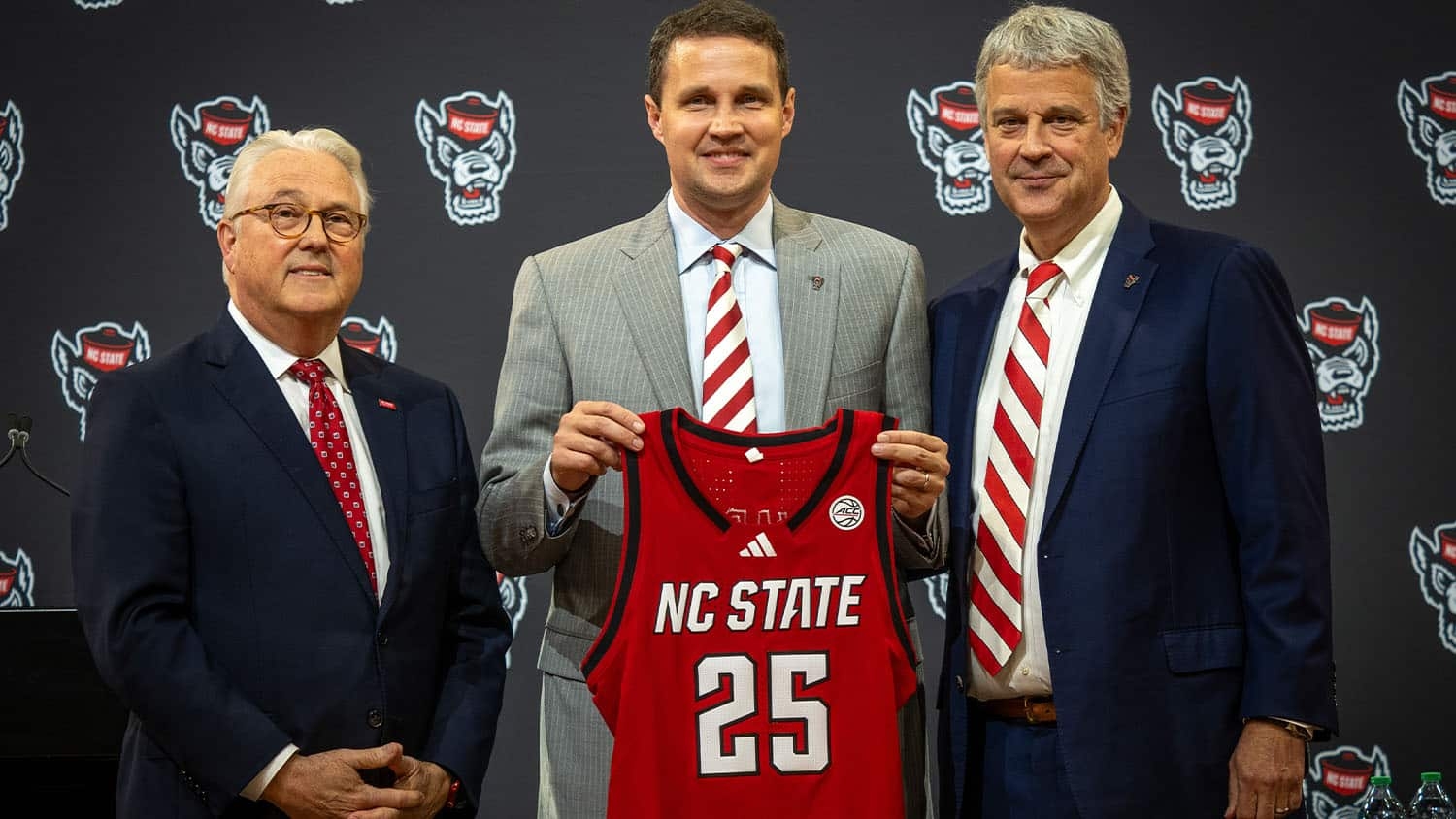 Will Wade stands between Chancellor Randy Woodson and Athletic Director Boo Corrigan while holding an NC State basketball jersey